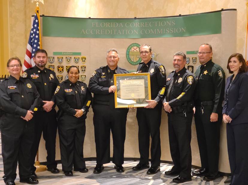 Corrections Chief Bryan Holt (center left) is joined with members of the Corrections team with the “Excelsior” recognition after being reaccredited by the Florida Corrections Accreditation Commission (FCAC).