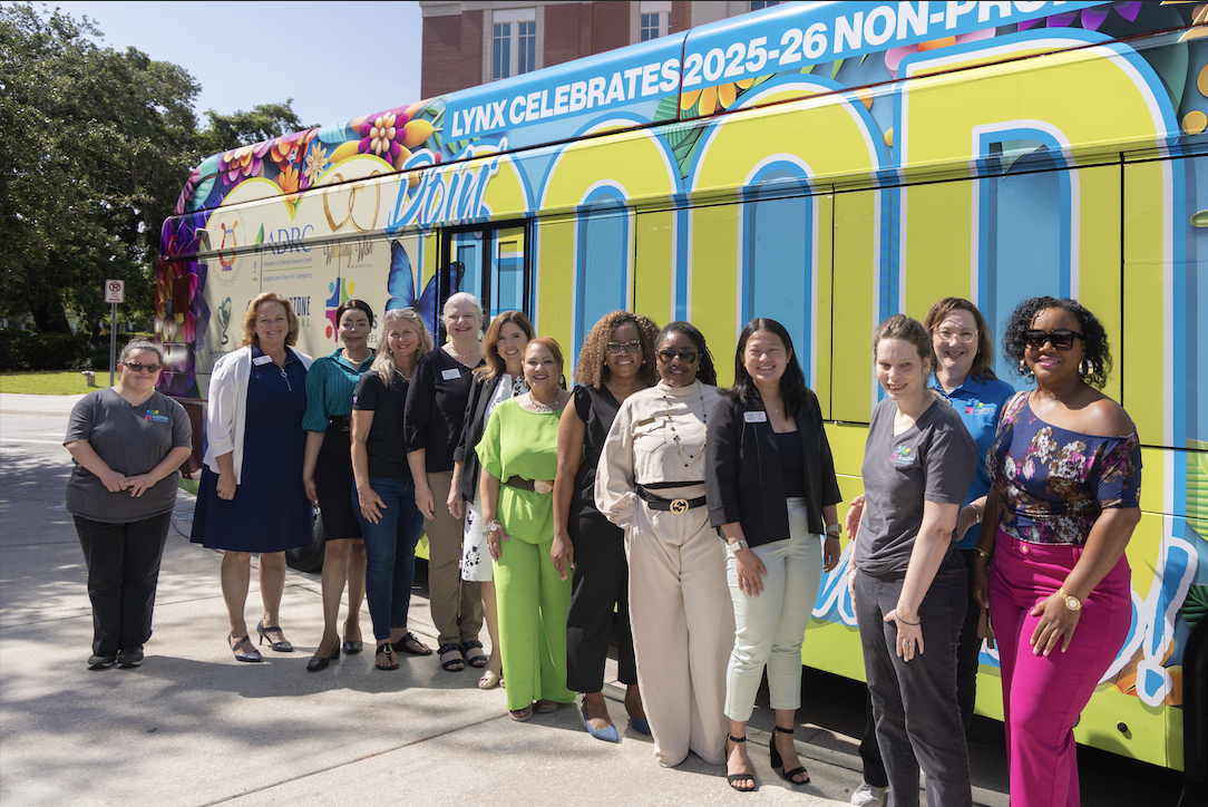 LYNX CEO Tiffany Holmer Hawkins (6th from L) and Osceola County Board of County Commissioners & LYNX Chairwoman Viviana Janer (7th from L) are joined by non-profit leaders and workers as LYNX unveils its 2025-26 Public Service Bus in Osceola County.